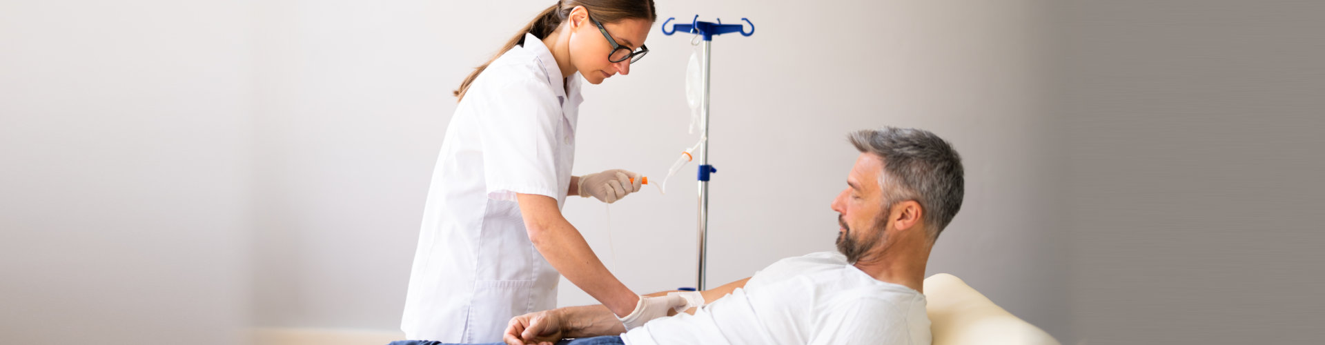 friendly nurse men or male doctor help sick senior elderly women patient in receiving IV drip infusion